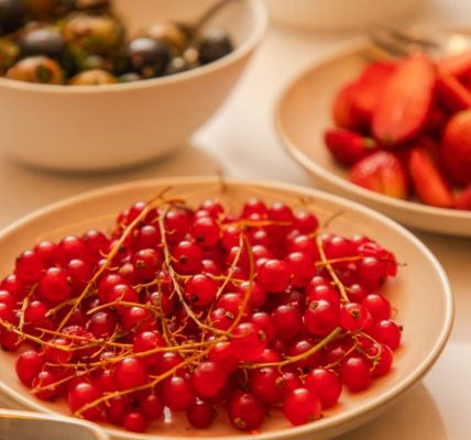 A vibrant display of fresh berries including red currants, strawberries, and grapes artfully arranged on a table.