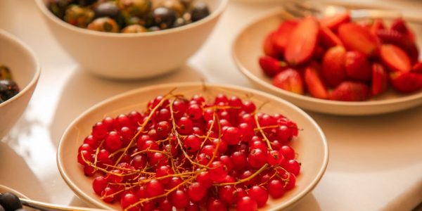 A vibrant display of fresh berries including red currants, strawberries, and grapes artfully arranged on a table.
