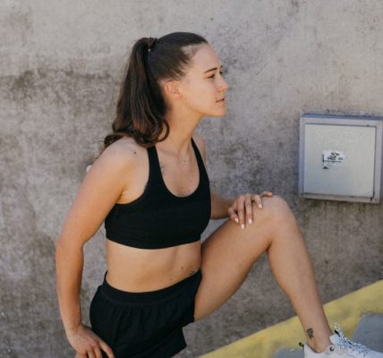 Woman in athletic wear stretching outdoors on steps, embodying wellness and fitness.
